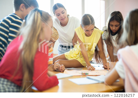 Schoolkids playing board game with teacher in classroom Schoolkids playing board game with teacher in classroom 122016257