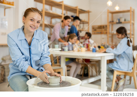 Girl working at a potter's wheel 122016258