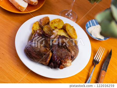 Roasted pork cheeks with baked potatoes and sauce Roasted pork cheeks with baked potatoes and sauce 122016259
