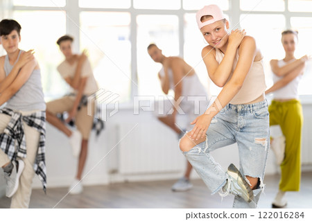Girl in baseball cap with two hair pigtails with group of teenage friends, learn to dance hip hop Girl in baseball cap with two hair pigtails with group of teenage friends, learn to dance hip hop 122016284