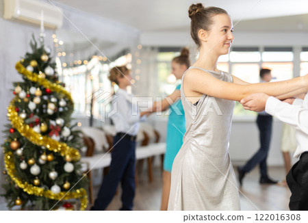 Teen boy and girl dancing waltz in couple during lesson at studio in New Year atmosphere 122016308