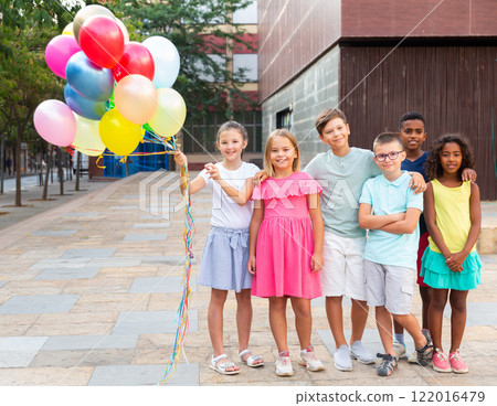 Full length portrait of happy tweens with balloons on city street 122016479