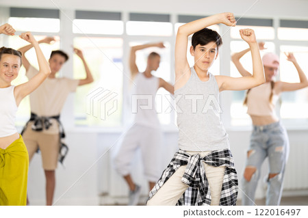 Teen guy together with group of teenage friends, learn to dance hip hop in choreographic hall. Teen guy together with group of teenage friends, learn to dance hip hop in choreographic hall. 122016497
