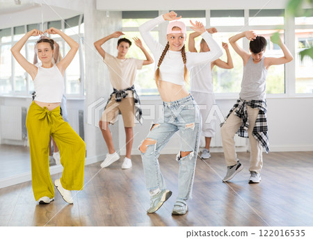 Teenage girl practicing basic hip hop moves in training hall Teenage girl practicing basic hip hop moves in training hall 122016535