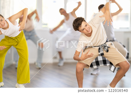 Teenage boy practicing basic hip hop moves in training hall 122016540