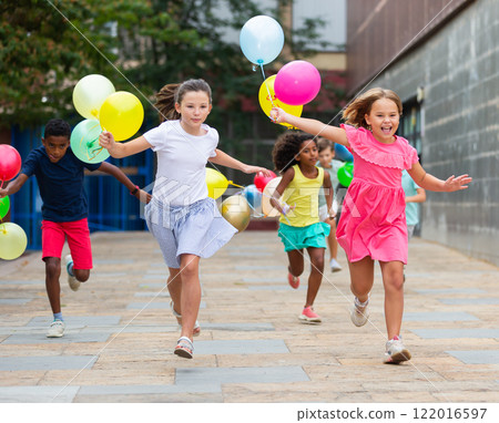 Boys and girls with balloons running thruogh streets Boys and girls with balloons running thruogh streets 122016597