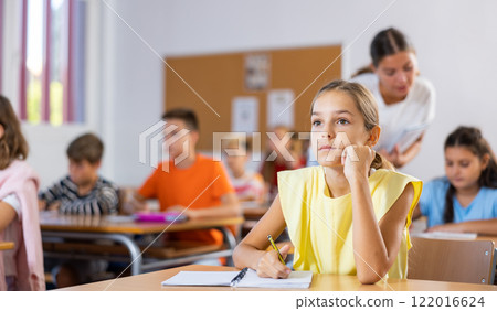 Schoolgirl are sitting at their desks and listens carefully to the teacher 122016624
