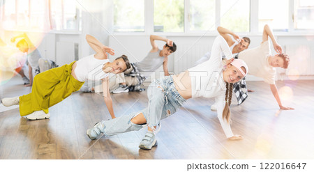 Group of teenagers in stylish clothes are training to dance low break and hip-hop in studio Group of teenagers in stylish clothes are training to dance low break and hip-hop in studio 122016647