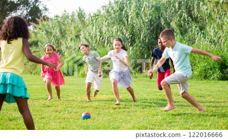 Active tweenagers playing football on green grass in summertime 122016666