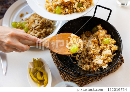 Female hands portioning Migas del pastor with grapes into plates Female hands portioning Migas del pastor with grapes into plates 122016734