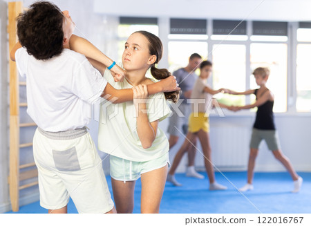 Girls and boys practicing in pair self defence movements with female trainer supervision Girls and boys practicing in pair self defence movements with female trainer supervision 122016767