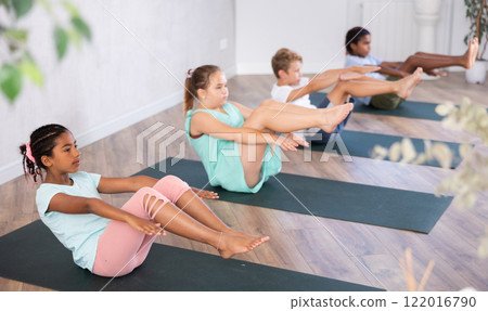 African girl perform boat asana - Paripurna navasana. Comprehensive hatha yoga class in mini group African girl perform boat asana - Paripurna navasana. Comprehensive hatha yoga class in mini group 122016790