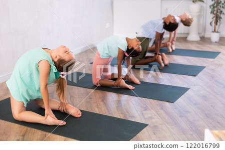 Female teen performs camel pose, Ushtrasana to improve mobility of spine and stretch muscles 122016799