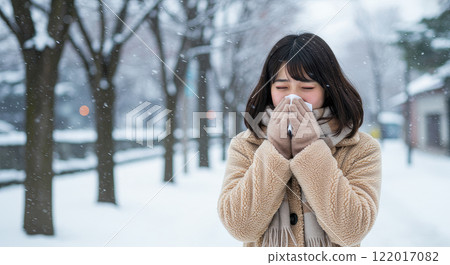 A young Japanese woman sneezing because she is cold 122017082