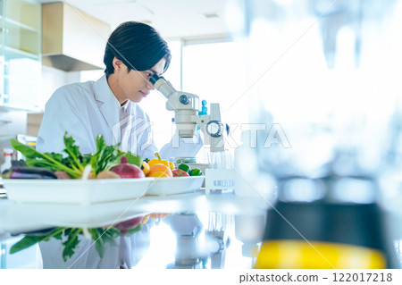 年輕研究員在顯微鏡下觀察蔬菜成分 註冊營養師 年輕研究員在顯微鏡下觀察蔬菜成分 註冊營養師 122017218