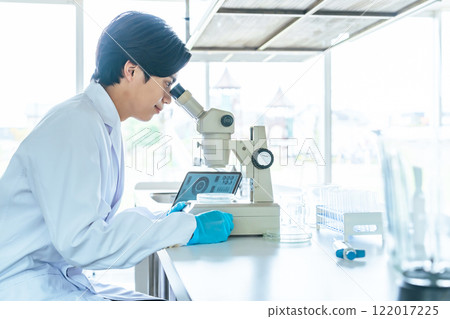 Male scientist observing with a microscope Male scientist observing with a microscope 122017225