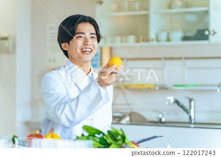 A young male registered dietitian in a white coat recommending vegetables and fruits 122017243