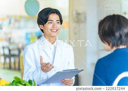 A young man in a white coat, doctor, counselor, talking with a woman 122017244
