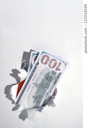 Dollar banknotes cash from the hole of ripped paper. Mockup or Copy space. Concept of business or finance Dollar banknotes cash from the hole of ripped paper. Mockup or Copy space. Concept of business or finance 122018594