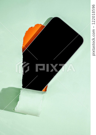 Blank mobile phone from the hole of ripped paper. Mockup or Copy space. Template. Concept of technology or communication Blank mobile phone from the hole of ripped paper. Mockup or Copy space. Template. Concept of technology or communication 122018596