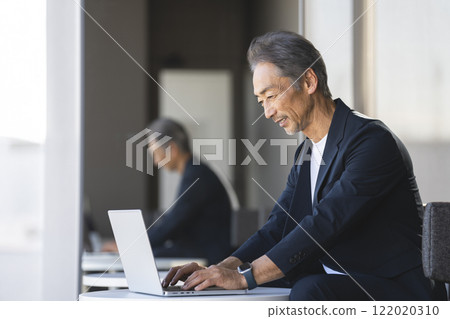 A senior businessman in his 60s working on a laptop 122020310