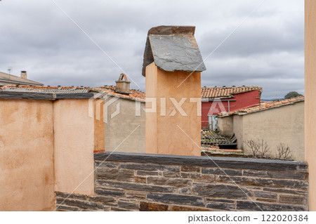 Rustic Chimney and Rooftops Under Cloudy Sky 122020384