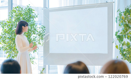 Young woman giving a presentation indoors with plenty of natural light - Natural 122020769