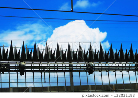 Stainless steel amulet (shinobi-gaeshi) on a railroad fence and blue sky 122021198