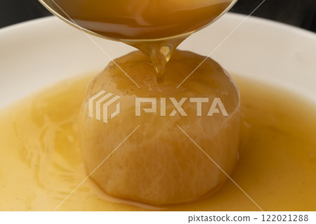 Pour soup stock over boiled radish with a ladle 122021288