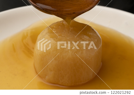 Pour soup stock over boiled radish with a ladle Pour soup stock over boiled radish with a ladle 122021292