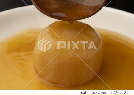Pour soup stock over boiled radish with a ladle 122021294