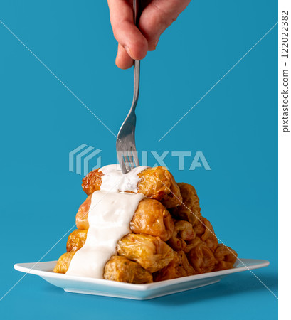 Cabbage rolls topped with sour cream sauce, minimalist on a blue table Cabbage rolls topped with sour cream sauce, minimalist on a blue table 122022382