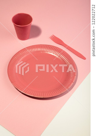 Pink disposable paper tableware for children's party on pink background. 122022712