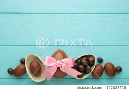 Easter chocolate egg with pink ribbon bow on blue background Easter chocolate egg with pink ribbon bow on blue background 122022716