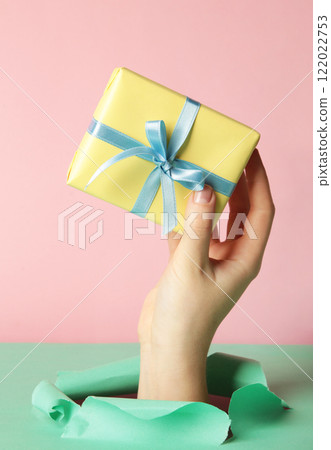 Female hand with gift box punching through the mint paper 122022753
