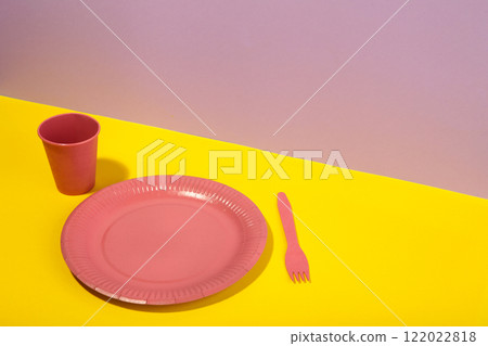 Pink disposable paper tableware for children's party on pink and yellow background. 122022818