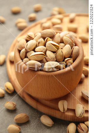 Pile of Pistachios on wooden bowl, pistachios on grey wooden background. Vrtical photo. Pile of Pistachios on wooden bowl, pistachios on grey wooden background. Vrtical photo. 122022824