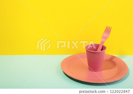 Pink disposable paper tableware for children's party on blue and yellow background. Pink disposable paper tableware for children's party on blue and yellow background. 122022847