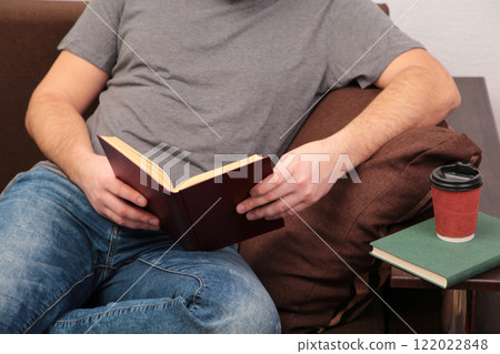 Man lying on sofa and reading book at home Man lying on sofa and reading book at home 122022848