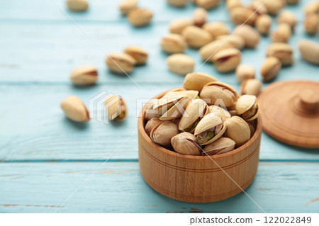 Pile of Pistachios on wooden bowl, pistachios on blue wooden background. Pile of Pistachios on wooden bowl, pistachios on blue wooden background. 122022849
