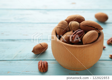 Pecan nuts on wooden bowl on blue wooden background. 122022853