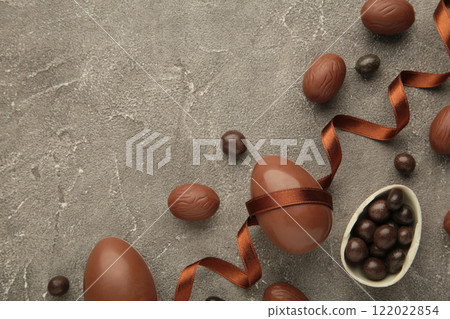 Easter composition with chocolate eggs and brown ribbon on grey background Easter composition with chocolate eggs and brown ribbon on grey background 122022854