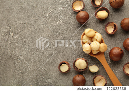 Macadamia nuts on wooden spoon on grey background. Top view. Macadamia nuts on wooden spoon on grey background. Top view. 122022886
