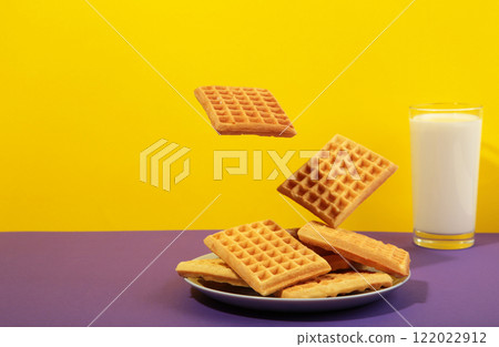 Belgian waffles flying in air on colorful background. Waffles in plate with milk and honey. Creative food concept. 122022912