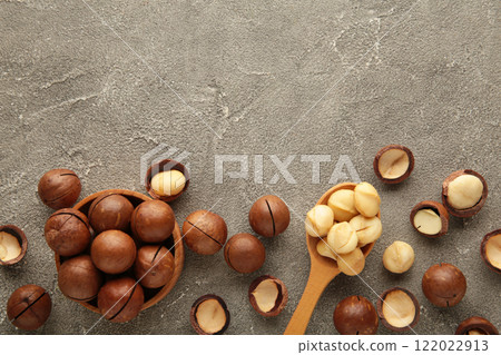 Macadamia nuts on wooden spoon on grey background. Top view. Macadamia nuts on wooden spoon on grey background. Top view. 122022913