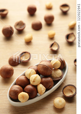 Peeled macadamia nuts on plate on light background. Vertical photo 122022941