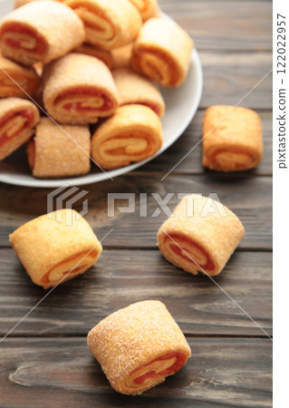 Homemade cookies, mini rolls with apricot jam in plate on brown wooden background. Vertical photo. 122022957
