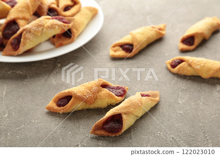 Tasty bagels with strawberry jam on grey concrete background. Homemade cookies Tasty bagels with strawberry jam on grey concrete background. Homemade cookies 122023010