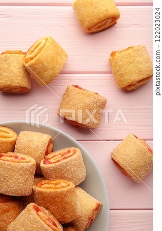 Homemade cookies, mini rolls with apricot jam in plate on pink background. Top view 122023024