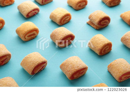 Homemade cookies, mini rolls with apricot jam on blue background. Top view 122023026